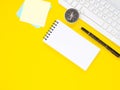 Blank notebook and pen with keyboard, compass, sticky note on yellow work place desk table. Top view with space for text.