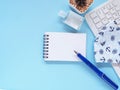 Blank notebook and pen with keyboard, hand sanitizer alcohol gel and medical face mask and cactus on blue work table. Royalty Free Stock Photo