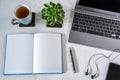 Blank notebook with pen and laptop, smartphone and cup of tea on white desktop Royalty Free Stock Photo