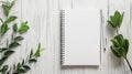 Blank notebook with pen and leaves on white wooden table. Space for text, flatlay, top view Royalty Free Stock Photo
