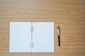 Blank notebook and a pen on wooden table with copy space