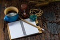 Blank notebook with pencil, coffee cup, hourglass and coffee beans on wooden table Royalty Free Stock Photo