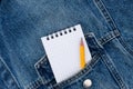 A blank notebook and pencil in workmans jeans pocket.