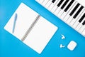 Blank notebook and piano on a blue background, flat lay, copy space.