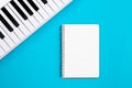 Blank notebook and piano on a blue background, flat lay, copy space.