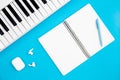 Blank notebook and piano on a blue background, flat lay, copy space.