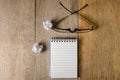 Blank notepad and eye glasses on wooden table