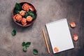 Blank notepad, flowers of coral roses and pencil on a dark rustic background.. Top view, flat lay feminine beautiful background