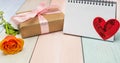 Blank notepad, heart and gift on a colored wooden background. Valentine`s day concept