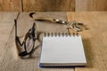 Blank notepad, key chain and eye glasses on wooden table