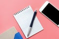 Blank notepad, organizer, phone and pen on pink background