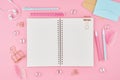 Blank notepad page in bullet journal on bright pink office desktop. Top view of modern bright table with notebook, stationery.