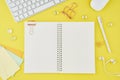 Blank notepad page in bullet journal on bright yellow office desktop. Top view of modern bright table with notebook, stationery.