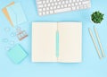 Blank notepad page for text on blue office desktop. Top view of modern bright table with notebook, keyboard. Mock up, copy space Royalty Free Stock Photo