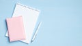 Blank notepad with pen and documents on blue background. Flat lay, top view office desk. Minimal style feminine workspace Royalty Free Stock Photo