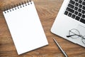 Blank notepad with pen and laptop computer are on top of wood office desk table. Top view, flat lay Royalty Free Stock Photo