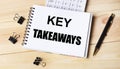 Blank notepad with text KEY TAKEAWAYS, pen, calculator and paper clips on office wooden table Royalty Free Stock Photo