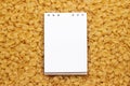 Blank notepad on uncooked macaroni background