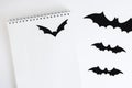 Blank notepad on white background with paper bats silhouettes, traditional Halloween decor. The concept of planning and organizing