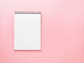 Blank notepad white page on pink desk, color background. Top vie