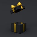 Blank open black gift box or opened black present box with gold ribbons and bow on dark black background with shadow