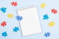 Blank open spiral paper notebook with blue, yellow, red pieces of puzzle on light blue background. World autism Royalty Free Stock Photo