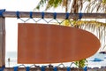 Blank orange vintage signboard in shape of surf board with copy space and palm tree in background Royalty Free Stock Photo