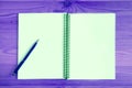 Blank page of an opened notebook with a blue pen on purple wooden table Royalty Free Stock Photo