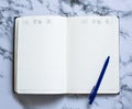 Blank page planner with blue pen on marble background