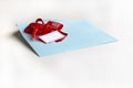 Blank paper blue envelope with red ribbon bow, letter for mail on white background, flat lay, top view. Concept postal service or Royalty Free Stock Photo