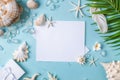Blank paper on blue pastel background with shells and starfish, empty note for holidays on beach Royalty Free Stock Photo