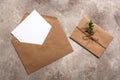 Blank paper card in brown envelope on beige textured background. Invitation cards template. Mockup for your design. Top view, flat