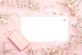 Blank paper card with gypsophila flowers and gift box on pink ba