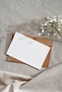 Blank paper card with mockup copy space, envelope and flowers on neutral beige background, aesthetic wedding invitation or