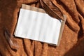 Blank paper card mockup, envelope and brown fall leaf on terracotta knitted cloth texture background with natural