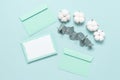 Blank paper card mockup with torn edges, envelopes, cotton flowers and eucalyptus branch on a mint blue background. Wedding