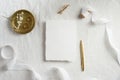 Blank paper card mockup, white ribbon, golden pen and rings on textile background. Top view, flat lay. Wedding invitation template Royalty Free Stock Photo