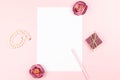 Blank paper card with pen, jewelry, flowers frame on pastel background. Top view, copy space. Royalty Free Stock Photo