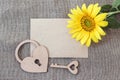 Blank paper card with sunflower, lock-heart and key on sacking.