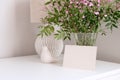 Blank paper card, vase of spring flowers, home decor on white table. Happy Mothers Day greeting card template in scandinavian Royalty Free Stock Photo