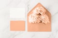 Blank paper cards and open retro peach fuzz envelope with peony flowers on white marble background Royalty Free Stock Photo