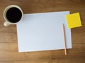 blank paper with coffee cup and note and pencil on wooden background