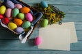 Blank paper, Forsythia branches and colorful Easter eggs on a light blue wooden background. Royalty Free Stock Photo