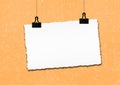 Blank paper frame hanged by clip on orange grunge wall background