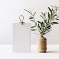 Blank paper gift tag, label mockup with rope and olive tree branch on white table. Created with Generative AI. Royalty Free Stock Photo