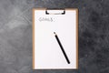 Blank paper with goals title and black pencil on grey table. Flat lay. Top view. New year concept. Free space. Copy Royalty Free Stock Photo