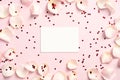 Blank paper greeting card, frame made of rose petals and red heart-shaped confetti on pink background. Happy Valentines Day Royalty Free Stock Photo