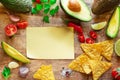 Blank paper and guacamole ingredients arranged as a frame on wooden background. Flat lay