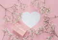 Blank paper heart-card and gift box with frame of delicate little white flowers on pink background from above. Flat lay style. Royalty Free Stock Photo