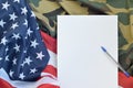 Blank paper lies on United States of America flag and folded military uniform jacket. Military symbols conceptual background Royalty Free Stock Photo